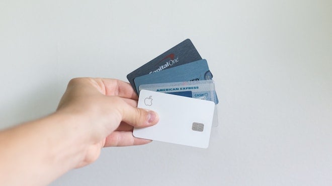 A person holding credit cards against a white background wall