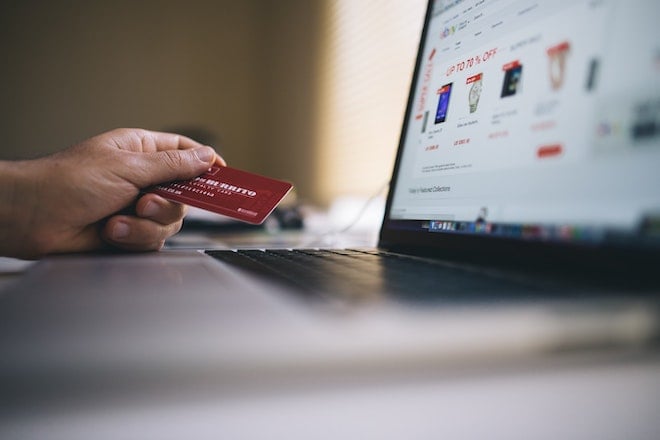person holding credit card shopping online at laptop