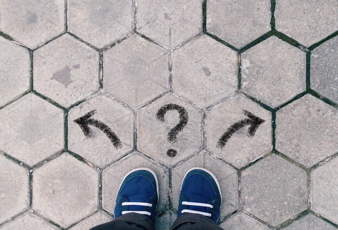Top view of blue shoes on tiled pavement with question mark and two arrows