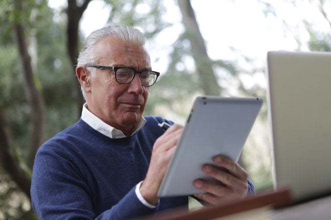 man in blue sweater holding tablet